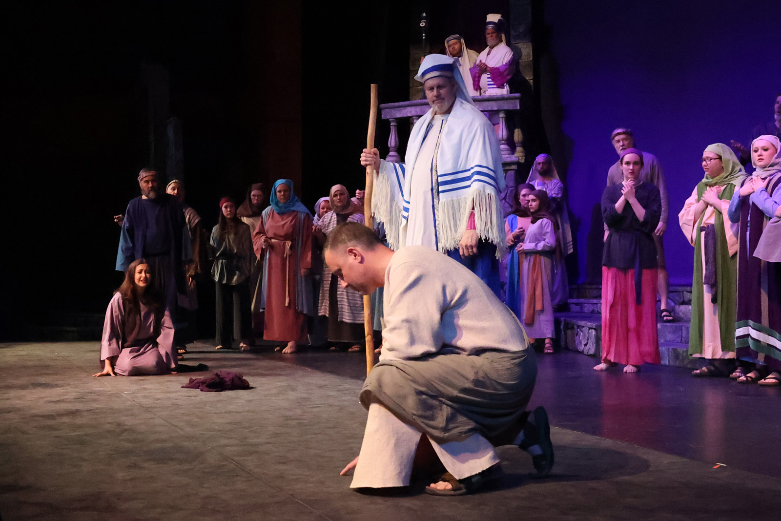A woman kneels on the floor as Jesus crouches near her.